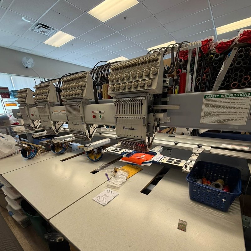 Four-head Barudan embroidery machine with hoops and cap frames along its table
