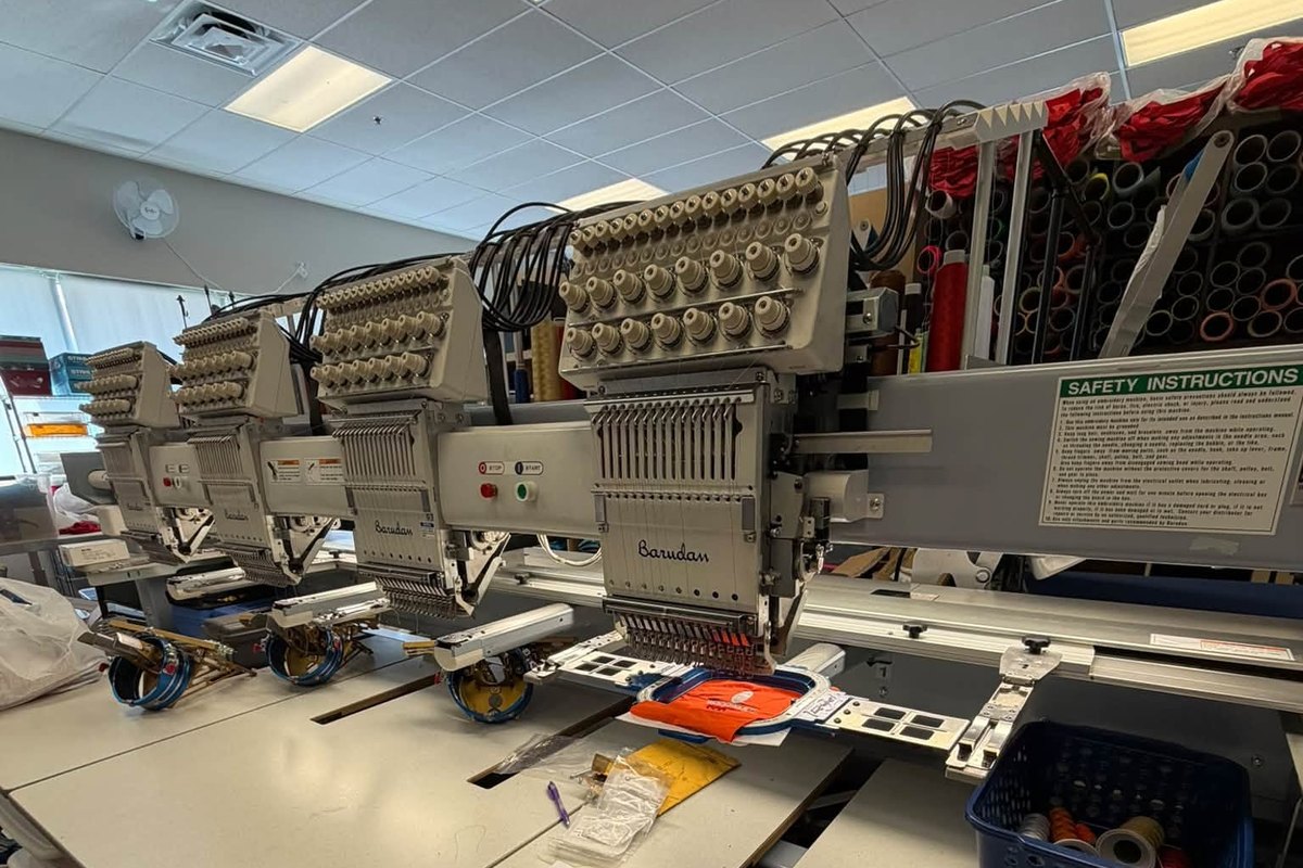 Four-head Barudan embroidery machine with an orange garment clamped under the nearest head