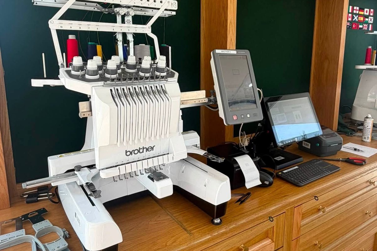 Brother ten-needle embroidery machine on an oak counter with spare hoops at the left