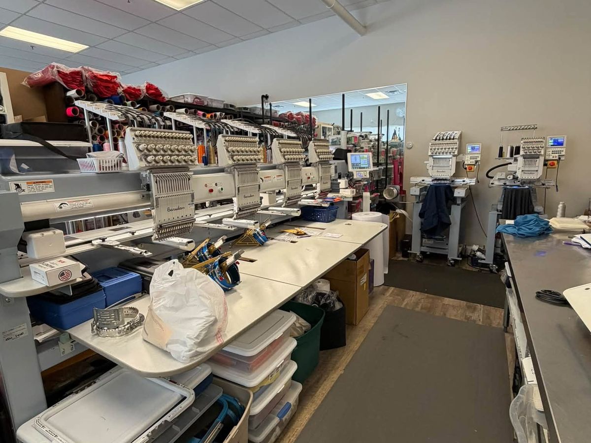Barudan four-head and two single-head machines along an embroidery shop aisle