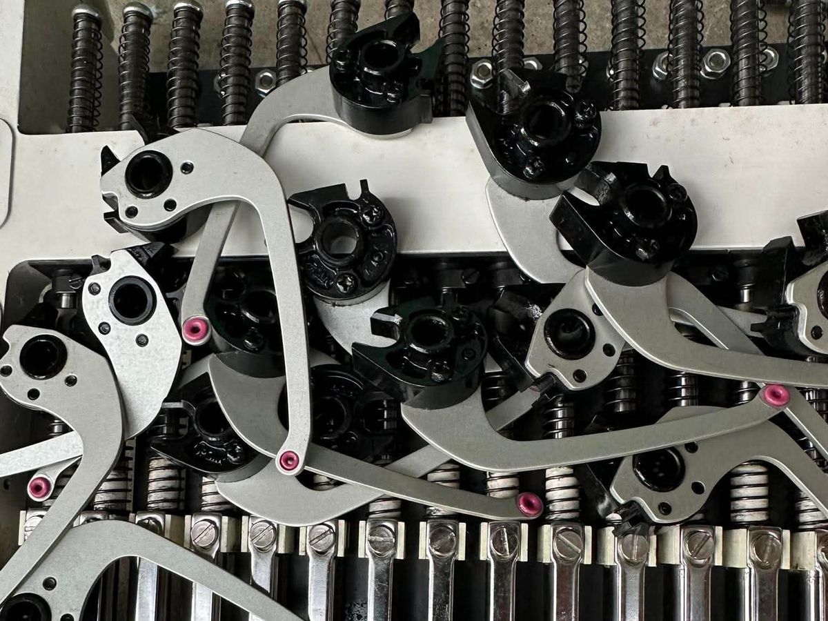 Take-up levers removed and laid across the needle bars of an opened sewing head