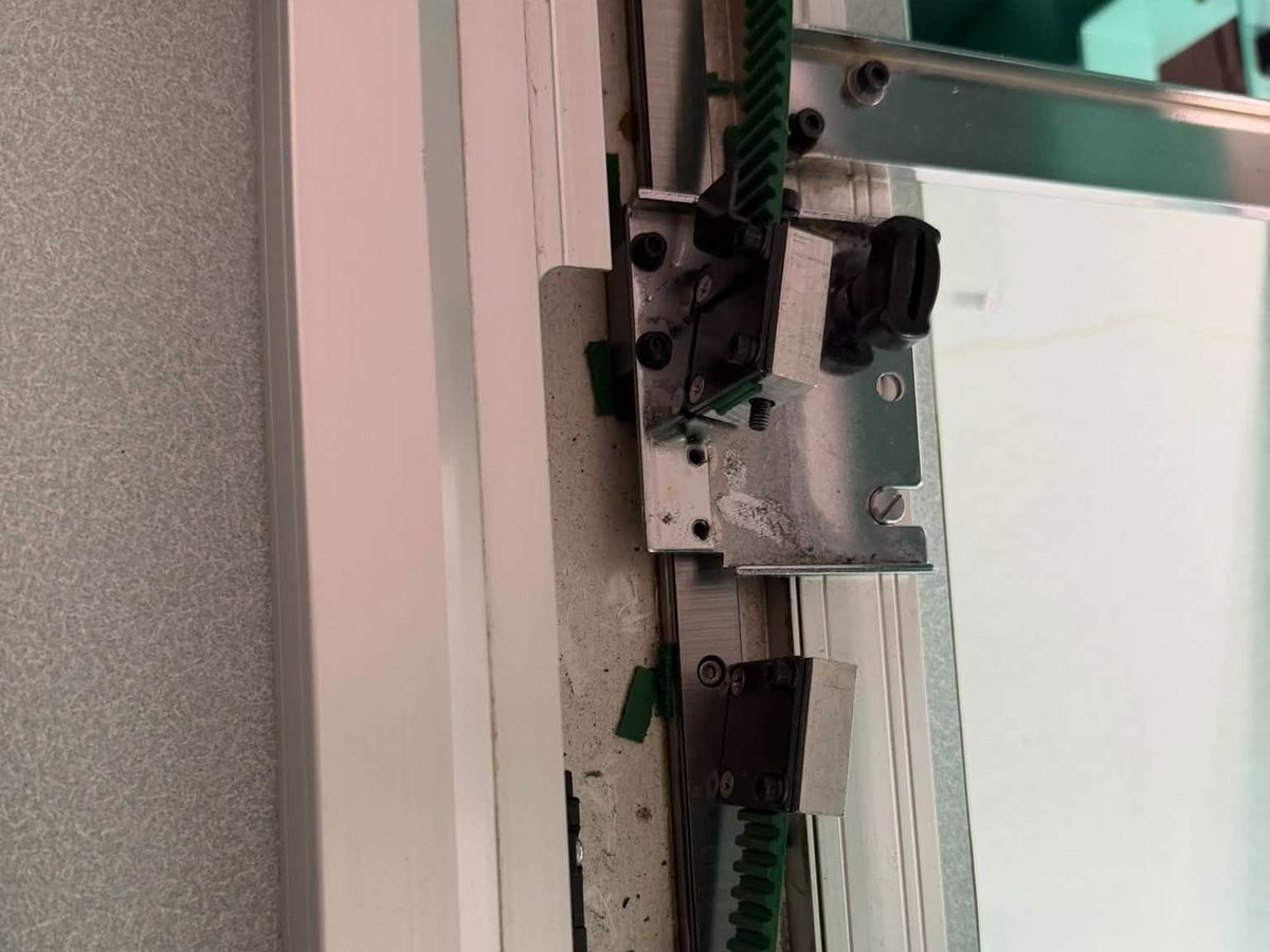 Opened frame drive with a green toothed belt running between two clamp blocks