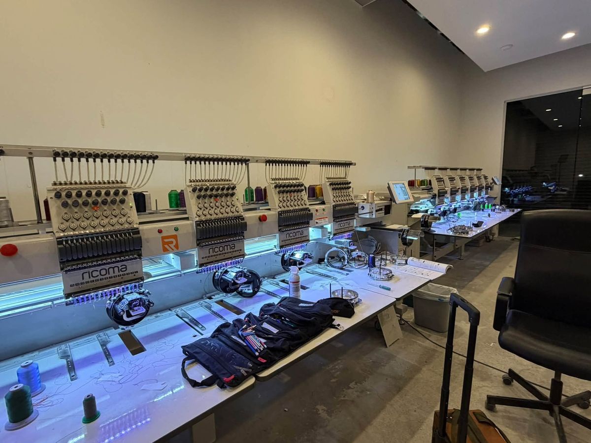 Row of Ricoma embroidery heads lit blue with a second Ricoma line behind