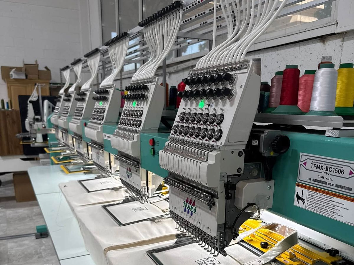 Tajima TFMX six-head stitching an outline design on cream canvas totes