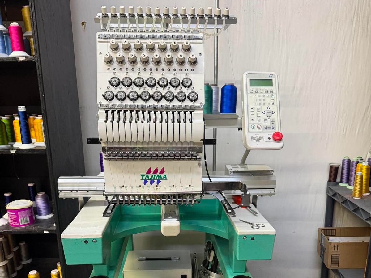 Tajima single-head with an LCD control panel and a tray of wrenches on its stand