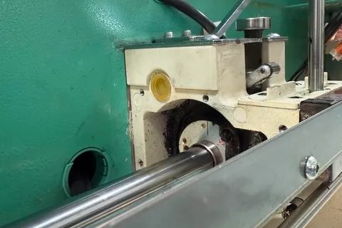 Main shaft and bracket on the side of a teal embroidery machine