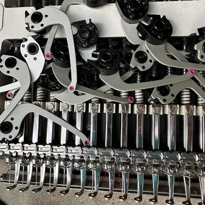 Disassembled sewing head with take-up levers and needle bar springs exposed