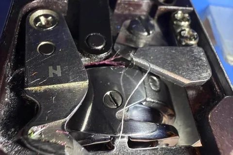 Thread trimmer knives beneath the needle plate of an embroidery machine