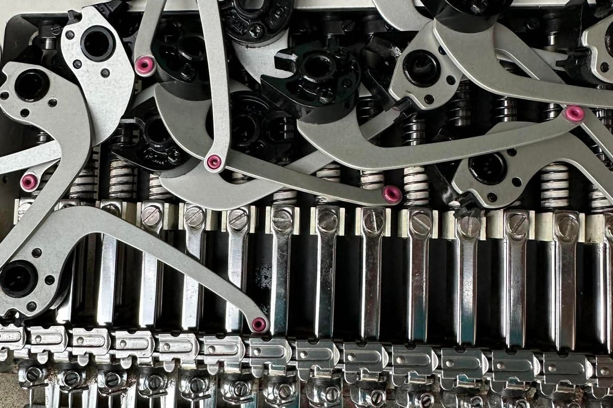 Opened embroidery machine sewing head with its take-up levers lifted off and resting on the needle bars