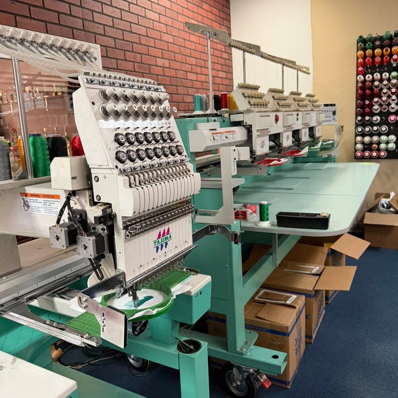 Single-head and multi-head Tajima machines side by side in a shop