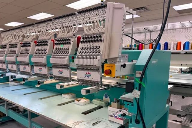 Multi-head teal Tajima embroidery machine in a production shop