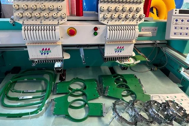 Two-head Tajima with green hoops and cap frames laid out on the table